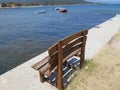 Brown bench with sea, boats, mountain and beach in background, Olimpiada, Greece