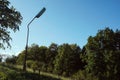 Lonely lamp in the nature - postapocalyptic city - green forest in the background