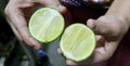 a photography of a person holding two limes in their hands, lemons are cut in half and held in a person's hands