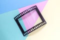 Photography picture frame in shape of vintage photo movie film strip negative on multicolored background minimalistic concept.