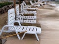 a photography of a row of lawn chairs on a beach, sea - coast chairs and umbrellas line the beach in front of a hotel Royalty Free Stock Photo