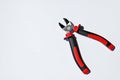 Photography of silver metal pliers with red and black rubber grips