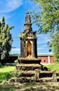 a photography of a small shrine in the middle of a field, monastery with a statue of a man on top of it