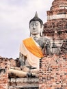 a photography of a statue of a buddha sitting on a ledge, statue of a buddha sitting on a ledge in front of a brick wall Royalty Free Stock Photo