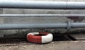 a photography of a tire sitting on the ground next to a metal pipe, balustraded tire on the ground next to a drain. Royalty Free Stock Photo