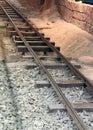 a photography of a train traveling down train tracks next to a tunnel, freight car on tracks in a tunnel with rocks and gravel Royalty Free Stock Photo