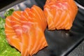 a photography of two pieces of salmon on a plate with lettuce, plate of sushi with lettuce and salmon on it