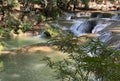 a photography of a waterfall with people standing on the rocks, valley with a waterfall and people walking on the side of it