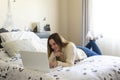 Photography of a woman teleworking in her bed from home smiling. Remote working woman