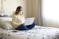 Photography of a woman teleworking in her bed in a video conference. Remote working woman