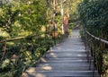 a photography of a wooden bridge with a person on it, balustraded wooden walkway with a wooden gate and a wooden bench Royalty Free Stock Photo