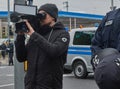 Photojournalist films with a professional video camera behind the police barrier