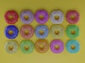 Photorealistic 3D render of colorful donuts on a yellow background.