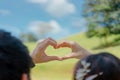 Photos from the back of a man and a woman raise a hand above the head and pose in heart shape. Royalty Free Stock Photo