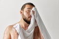 Photoshoot of man looking away and wiping towel after washing over light grey background. Royalty Free Stock Photo