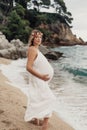 Photoshoot of a pregnant woman walking on the beach