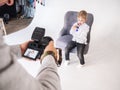 Photographer man photographs a little boy in a white shirt on a white background. Royalty Free Stock Photo