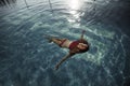 Photoshoot in the swimming pool full of clear blue water with bronzed beautiful model who is relaxing, enjoying the nature fusion