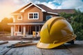 PhotoStock Yellow safety helmet on table with backdrop of house under construction photo Royalty Free Stock Photo