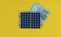 Photovoltaic panel , money and plug wire isolated on yellow background. olar panel with varied values of Brazilian money Royalty Free Stock Photo