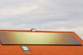 Photovoltaic or solar panels on roof of the house at sunset. Red roof with ecological solar system during the summer day. Clouds Royalty Free Stock Photo