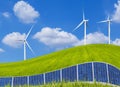 Photovoltaics solar panels and wind turbines on green field Royalty Free Stock Photo