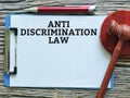 Phrase anti discrimination law written on paper clipboard with a pen and gavel.