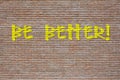 Phrase Be Better spray painted in yellow on a brick wall
