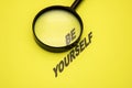 phrase be yourself on a yellow background, the word be magnified with a magnifying glass Royalty Free Stock Photo