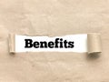 Phrase Benefits appearing behind torn brown paper. Royalty Free Stock Photo