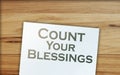 The phrase Count Your Blessings typed on a piece of paper and paper dollar signs around. Career concept