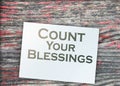 The phrase Count Your Blessings typed on a piece of paper and paper dollar signs around. Career concept