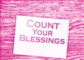 The phrase Count Your Blessings typed on a piece of paper and paper dollar signs around. Career concept