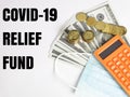Phrase COVID-19 RELIEF FUND with calculator,face mask,coins and dollar bank notes.