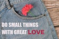 Phrase DO SMALL THINGS WITH GREAT LOVE written on blue jeans with flower Royalty Free Stock Photo