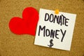 A yellow sticky note writing, caption, inscription Phrase DONATE MONEY in black ext on a sticky note pinned to a cork Royalty Free Stock Photo