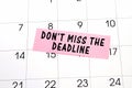 The phrase Dont miss the deadline written in black text on a pink sticky note posted to a calendar page as a reminder. Close up of Royalty Free Stock Photo