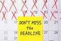 The phrase Dont miss the deadline written in black text on a yellow sticky note posted to a calendar page as a reminder. Close up Royalty Free Stock Photo