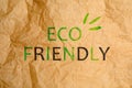 Phrase Eco Friendly written on crumpled kraft paper, top view