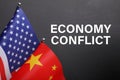 Phrase ECONOMY CONFLICT, USA and China flags on black background, closeup