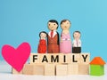 Phrase FAMILY on wooden cubes with dolls,heart shape and house blocks.