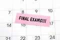 The phrase Final Exams written on a pink sticky note posted on a calendar or planner page. Deadline concept read a reminder on Royalty Free Stock Photo