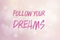 Phrase follow your dreams on a pink background with shiny bokeh and bright light