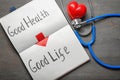 Phrase Good health - good life written in notebook with stethoscope on grey background Royalty Free Stock Photo