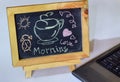 Phrase Good Morning coffee written on a chalkboard on it and smartphone, laptop