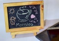 Phrase Good Morning coffee written on a chalkboard on it and smartphone, laptop