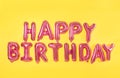 Phrase HAPPY BIRTHDAY made of pink foil balloon letters on background