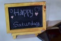 Phrase Happy saturday written on a chalkboard on it and smartphone, laptop