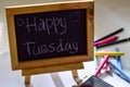 Phrase happy tuesday written on a chalkboard on it and smartphone, colorful chalk. Royalty Free Stock Photo