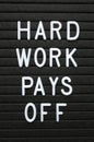 The phrase Hard Work Pays Off in white letters on a notice board